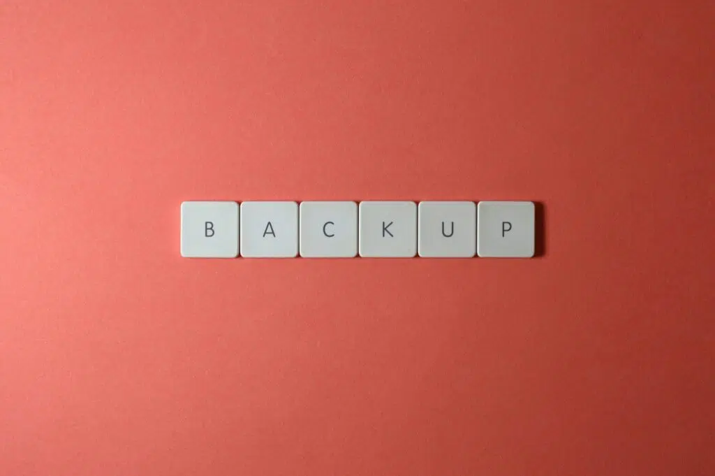 Free Close-up of keyboard keys spelling 'BACKUP' placed on a coral-colored surface. Stock Photo